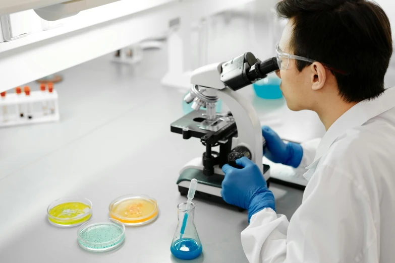 a man in white lab coat looking into a microscope