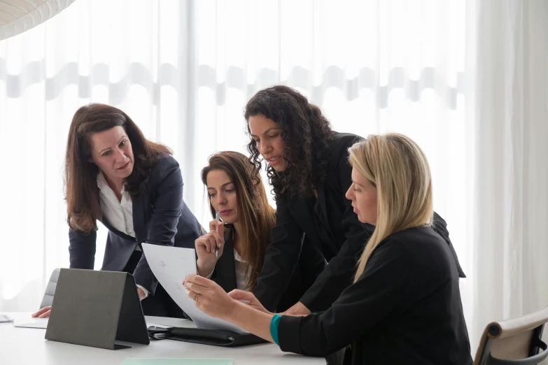 four women in business attire are having a meeting