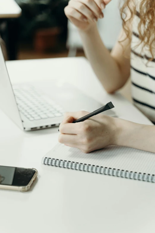 a person with their hand on the pen while sitting at a table