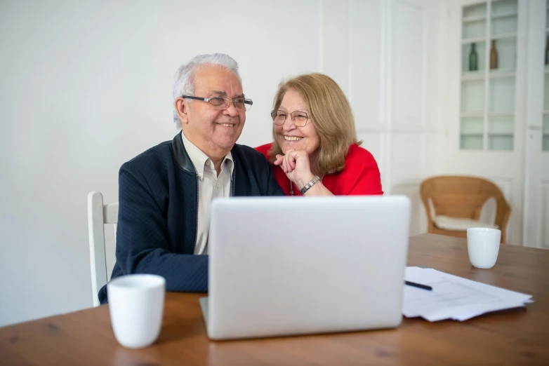 a man and woman smiling while looking at a laptop