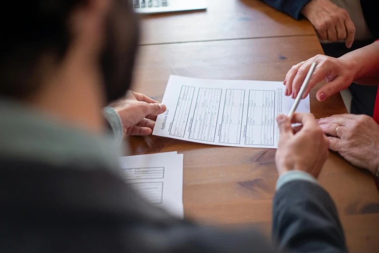 four people sitting around a table doing paperwork