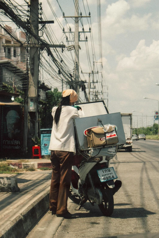 a man riding on the back of a moped with luggage on it