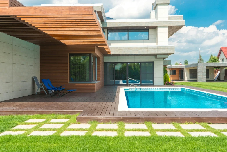 a pool surrounded by lawn chairs near a home