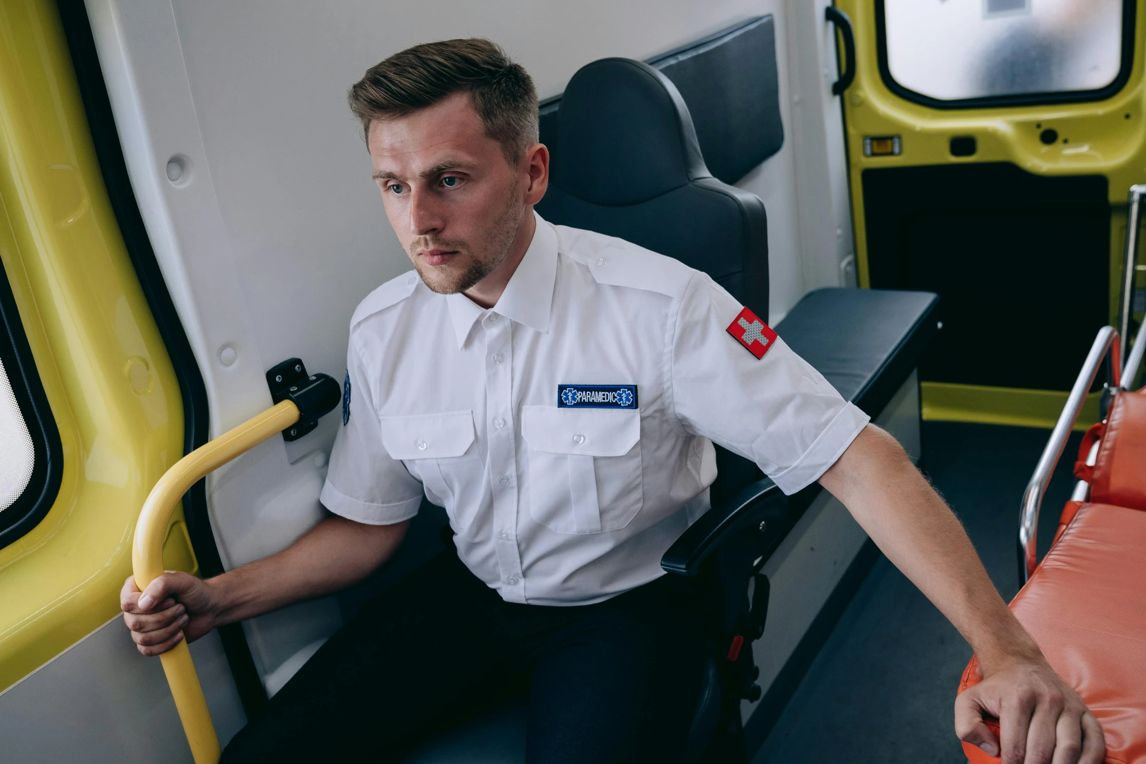 the man is sitting down inside of a train with his hand on the door