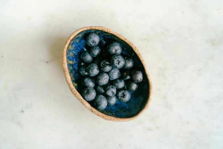 blueberries in a bowl on white surface