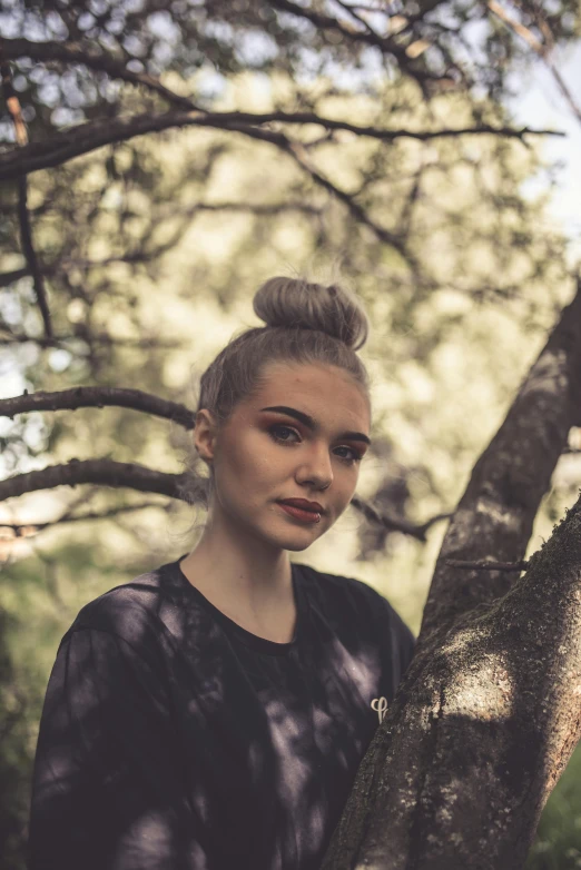 a female with a ponytail stands in front of a tree