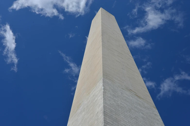 the washington monument is surrounded by clouds and blue sky