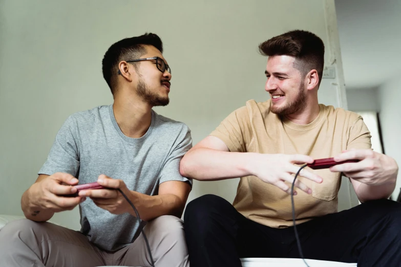 two men sitting on a couch playing the nintendo wii