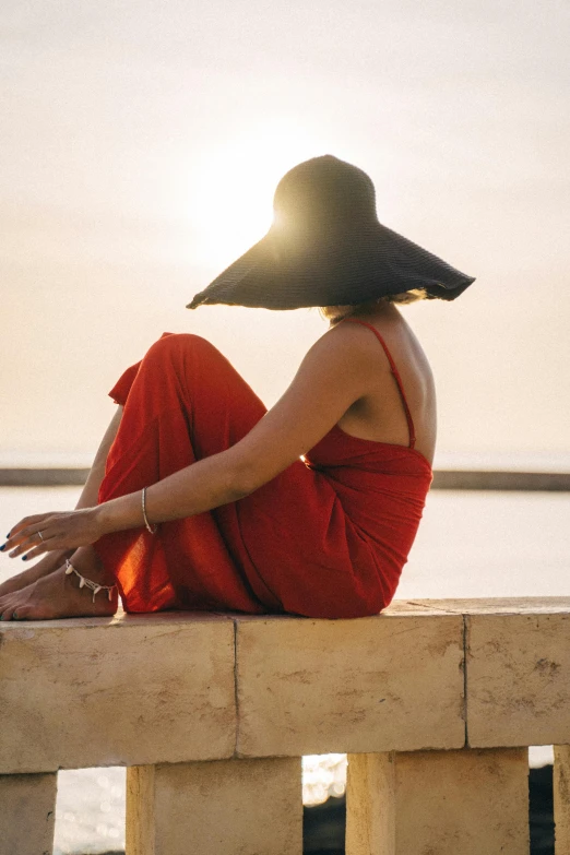 a person sitting on a ledge in red at sunset