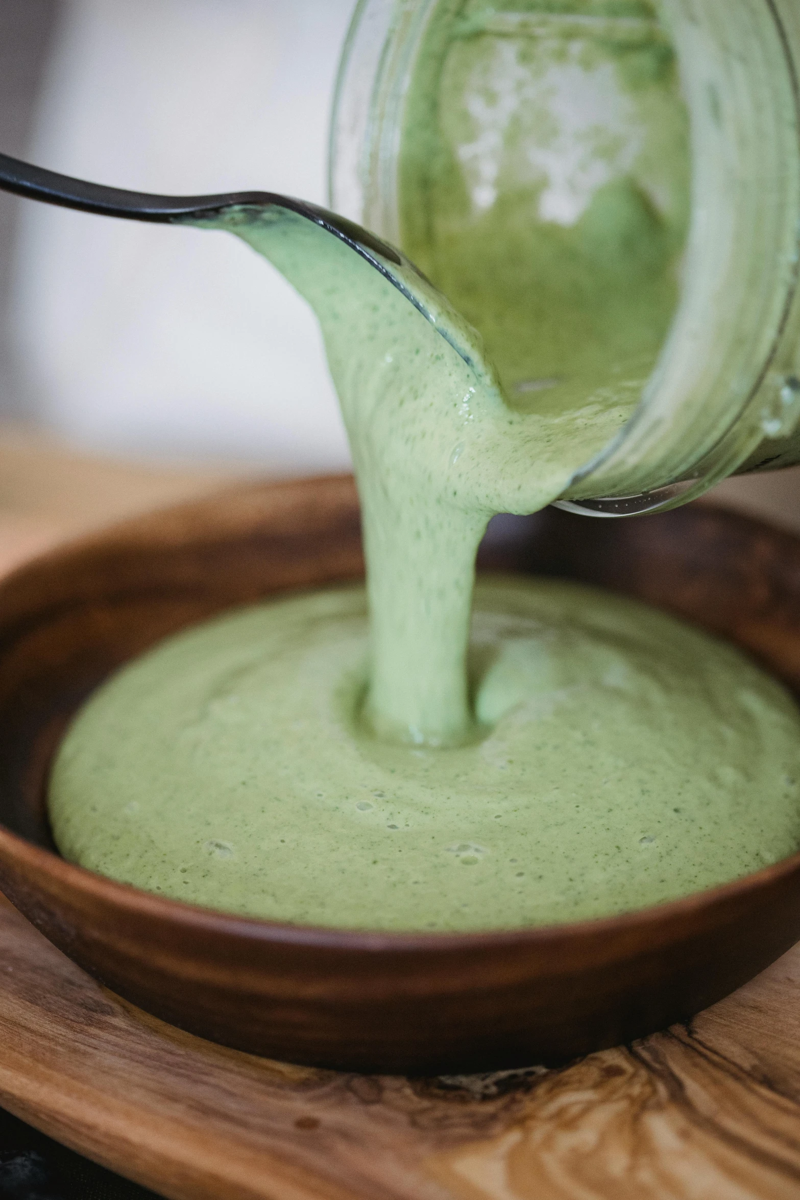 a spoon in a bowl full of green liquid