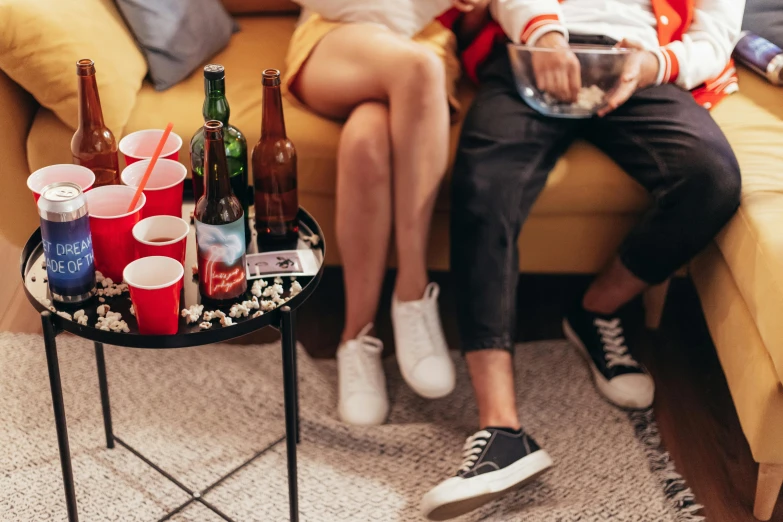 a couple sitting on a couch with beer bottles