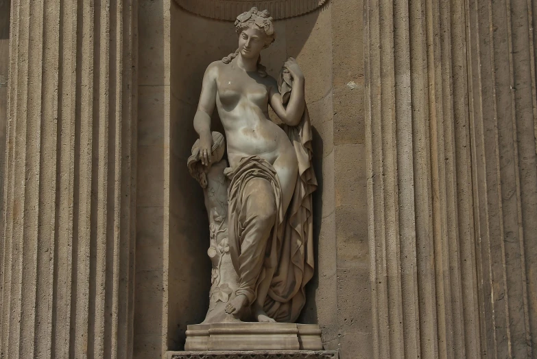 a statue sitting outside of a building near stone pillars