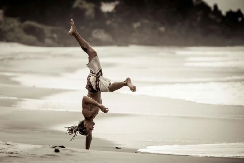 a man doing an acrobatic stand on the beach