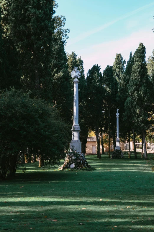 a stone pillar stands in the center of a green park