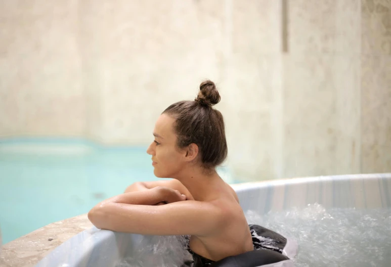 a woman is relaxing in a  tub by a pool