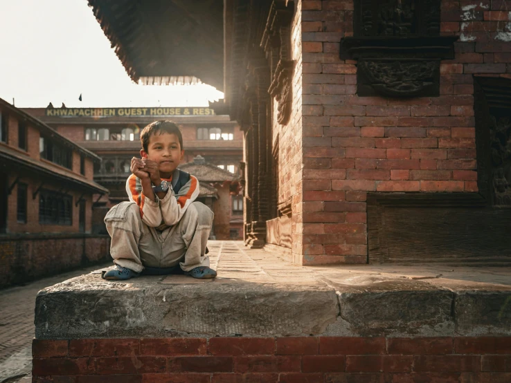 the young child is seated on a brick platform