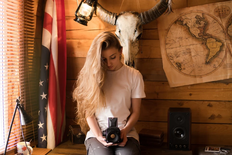 the woman is holding a camera and sitting down