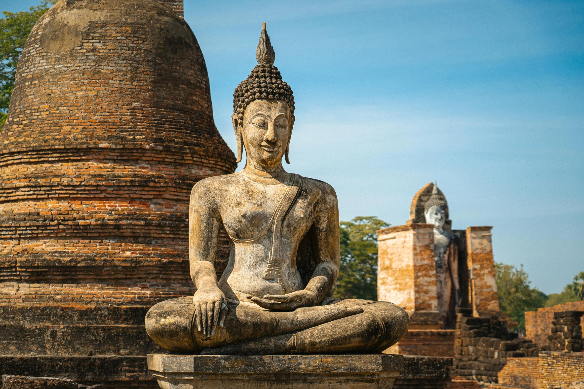 a buddha statue sitting next to large bricks