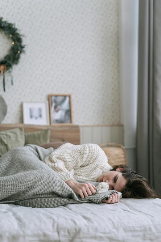 a woman laying in bed under blankets on top of a blanket