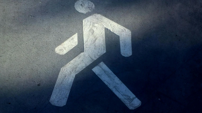 there is a white pedestrian sign with a shadow on it