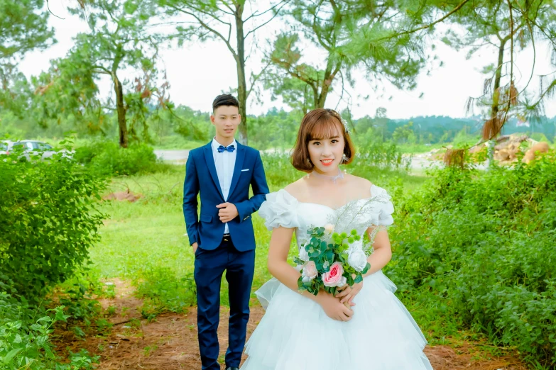 the bride is in front of the groom, in the woods