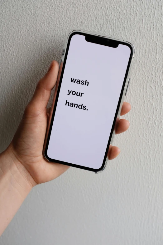 someone holding a phone that reads, wash your hands