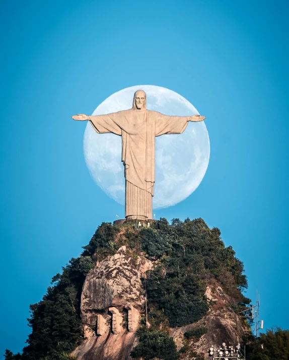 the moon is lit above the christ statue