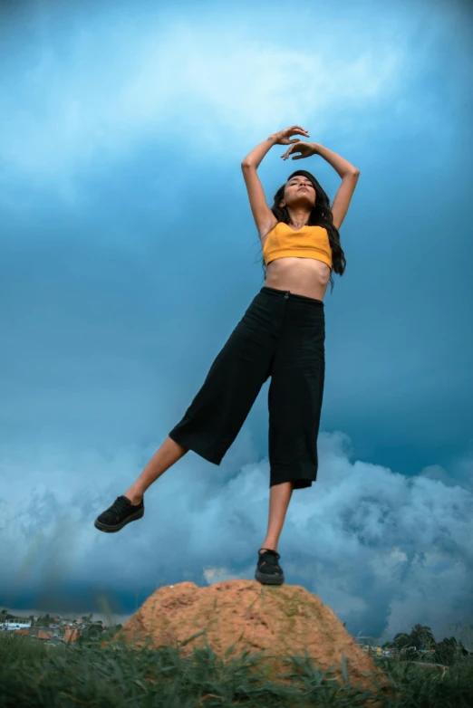 woman in black and yellow shirt standing on top of a mound of dirt