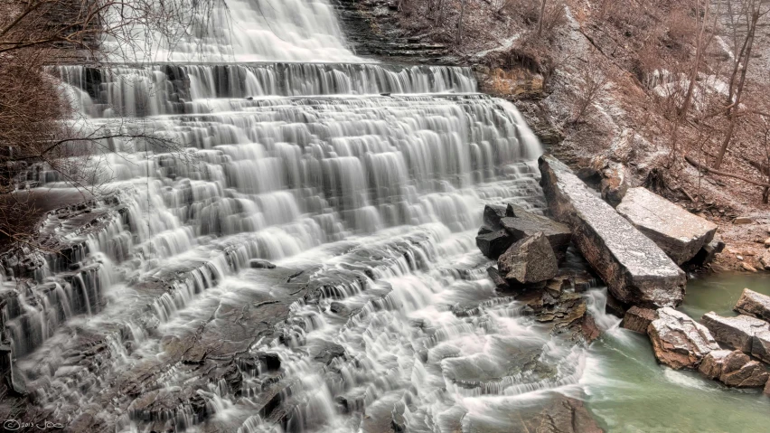 a large waterfall surrounded by snow covered rocks