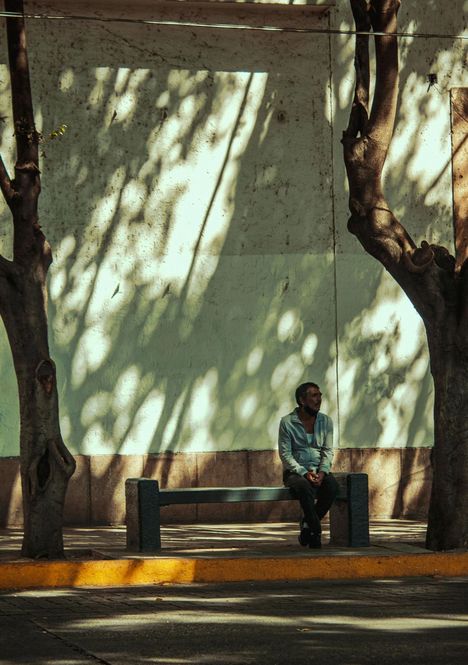 a man sitting on top of a wooden bench next to trees