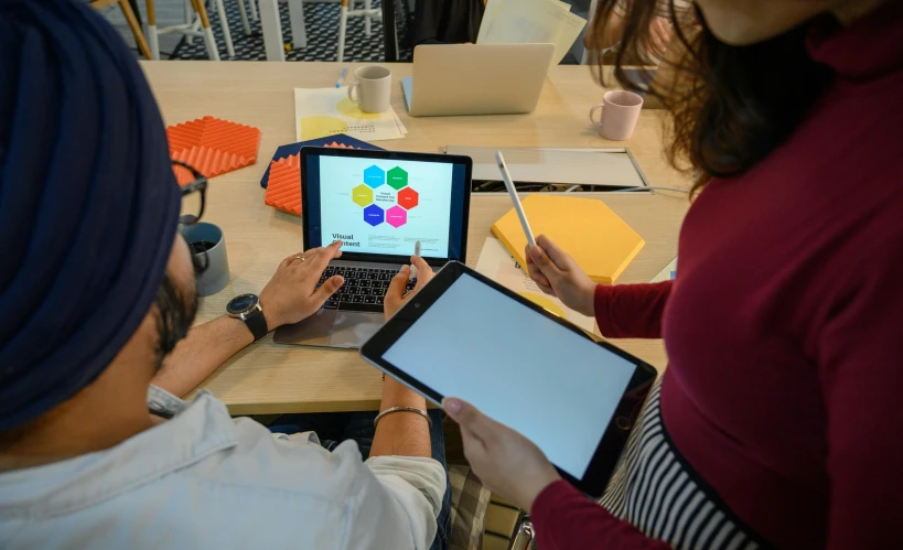 three people working on electronic devices with a table