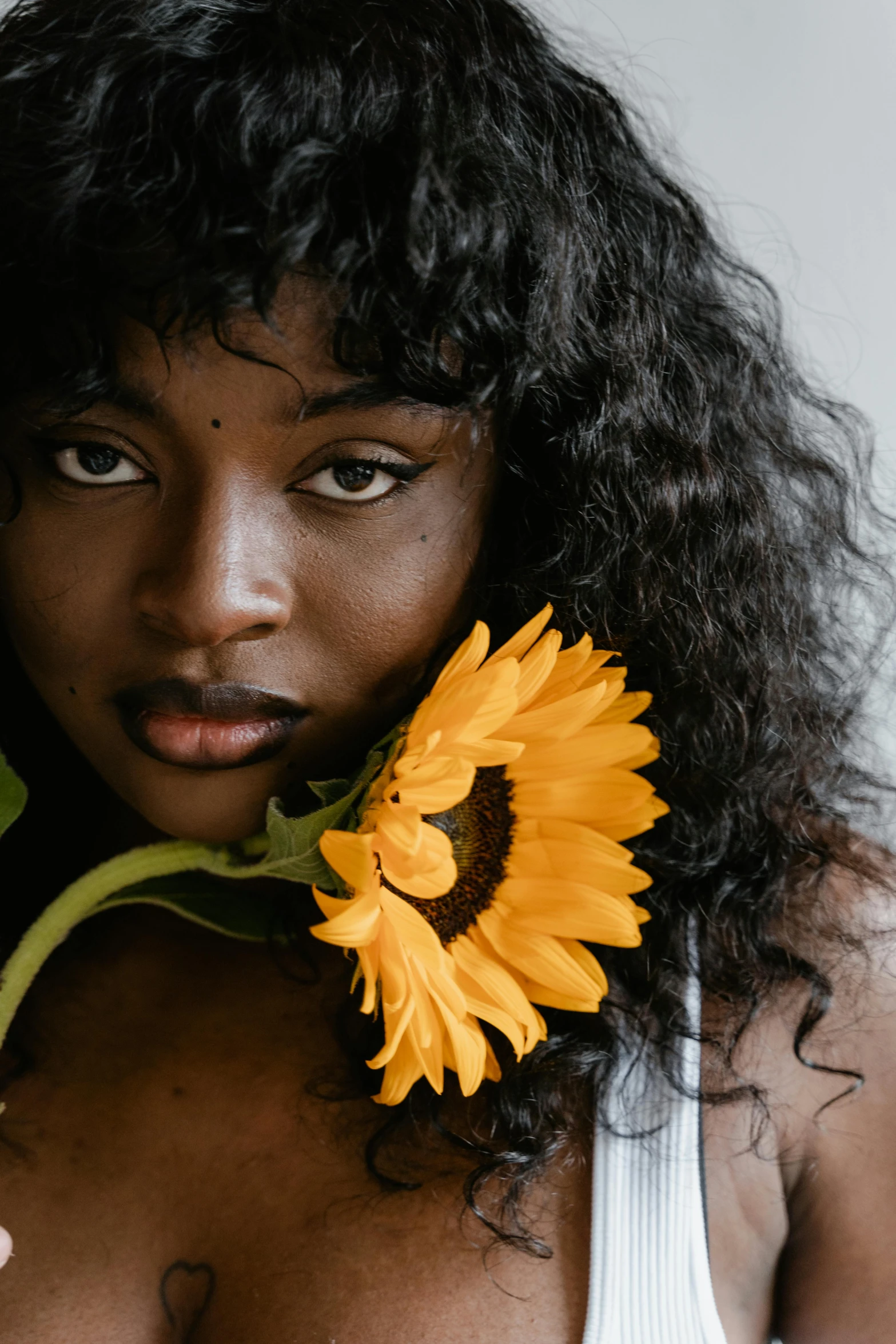 a beautiful woman holding a yellow flower in her left shoulder