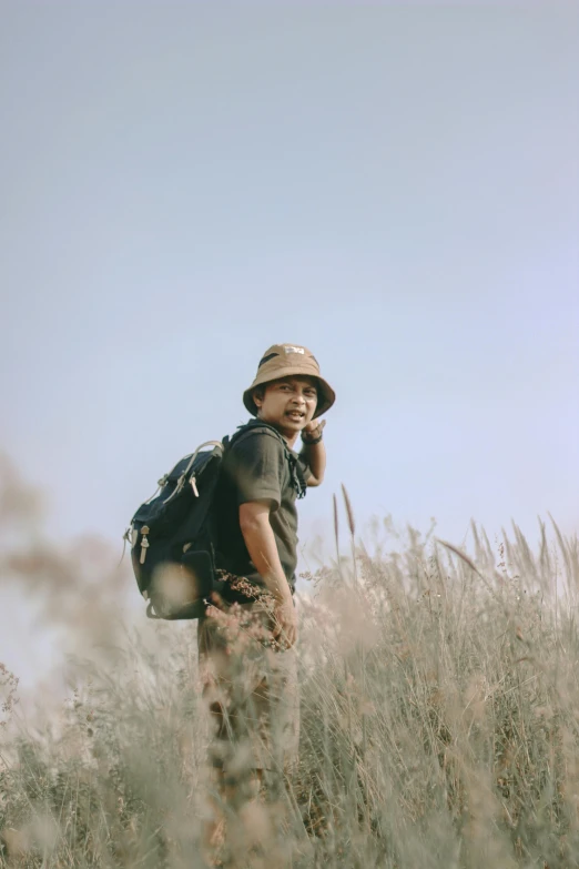 a man stands in a field while talking on his cell phone