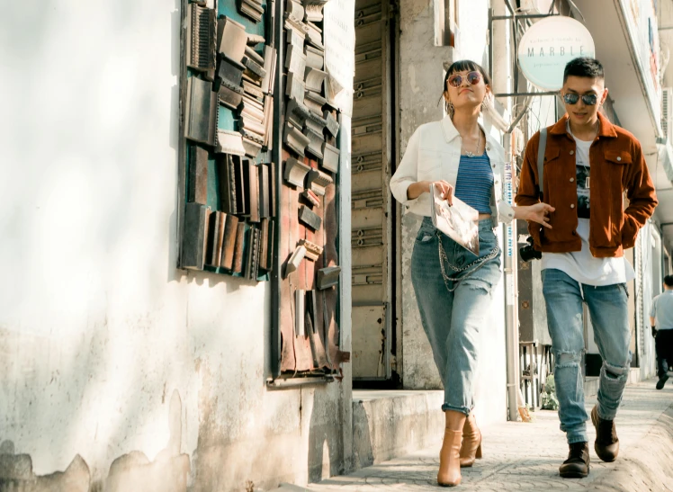 two people walking on the street in front of a building