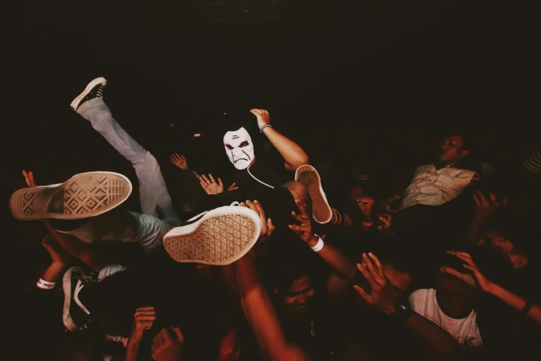 two people in the air, one jumping while others hold their arms up to touch the audience