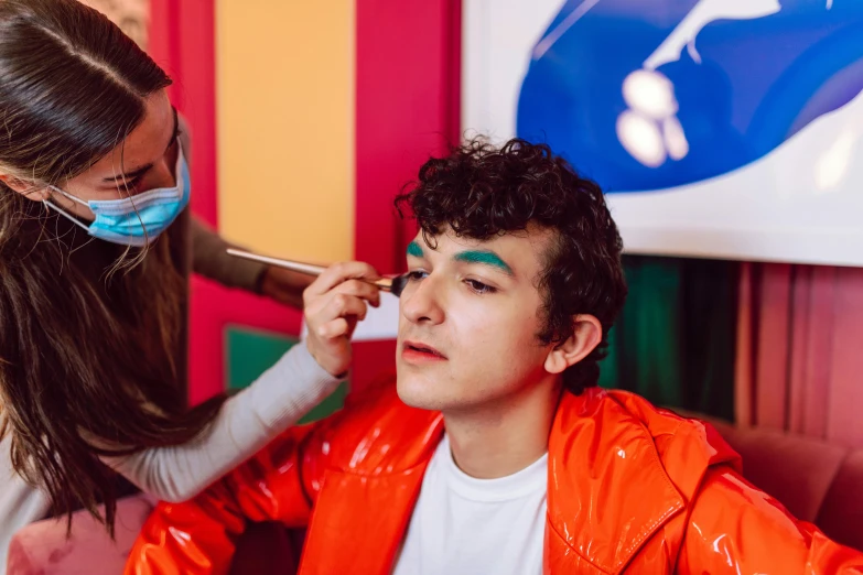 a child getting his face painted as a person in a medical mask