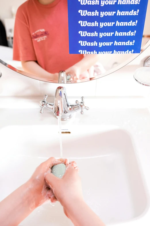 a person washing their hands under a bathroom sink
