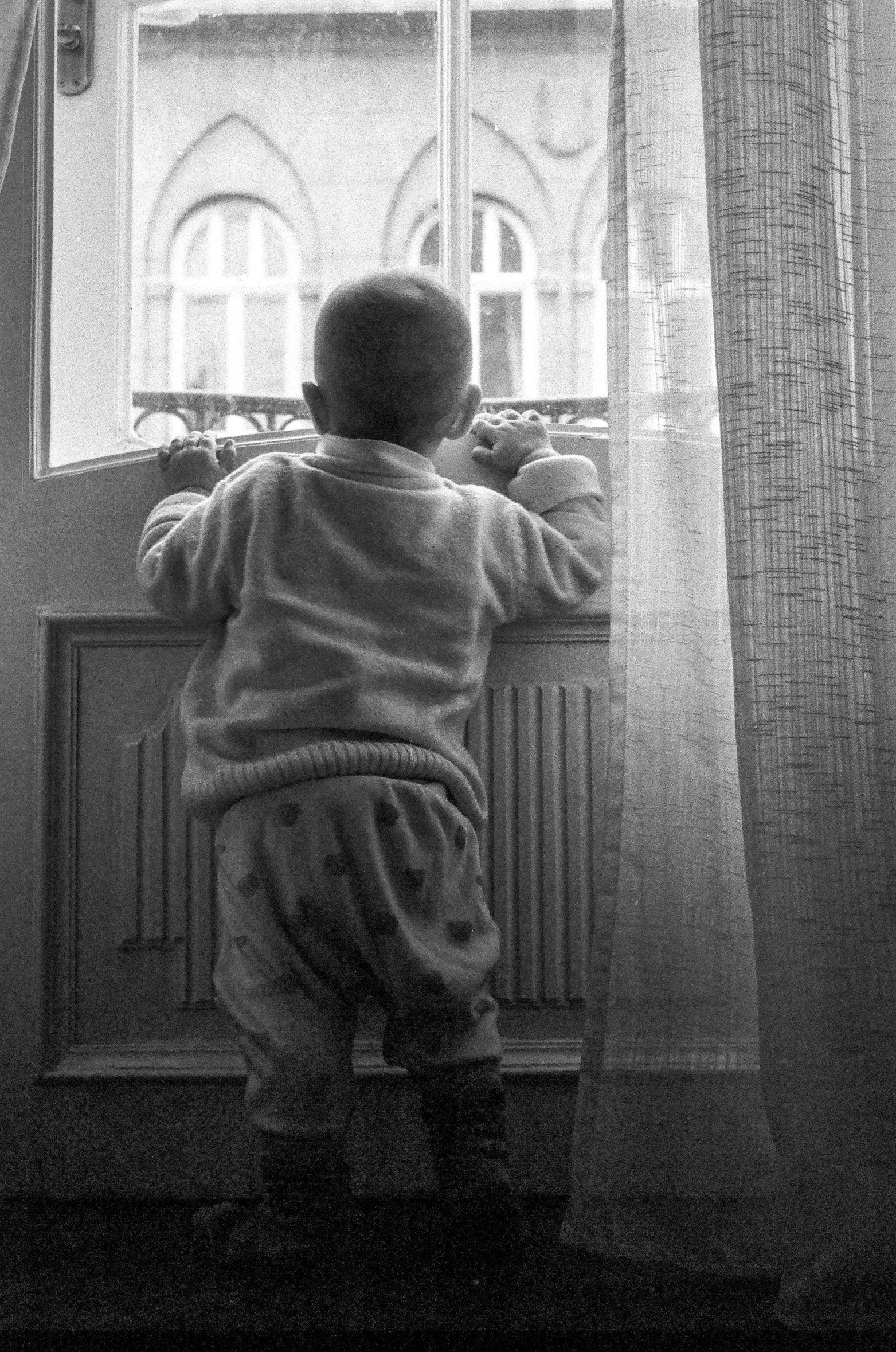 a boy looking out a window at the outside