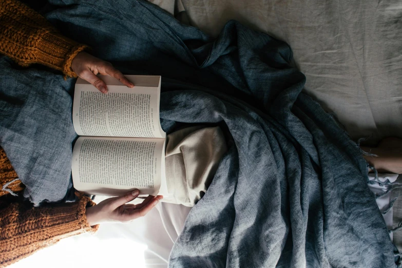 two people are lying down with open books