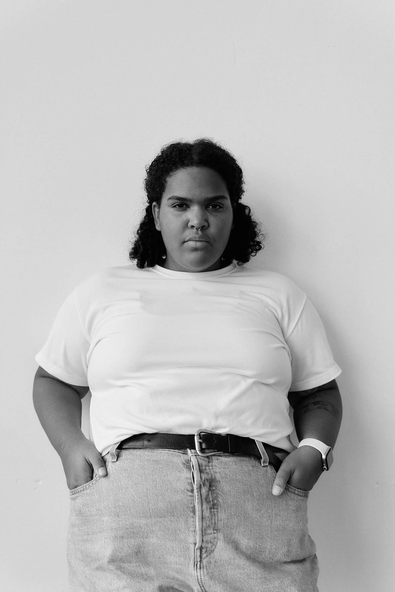 woman wearing a short skirt and white top stands in front of a wall