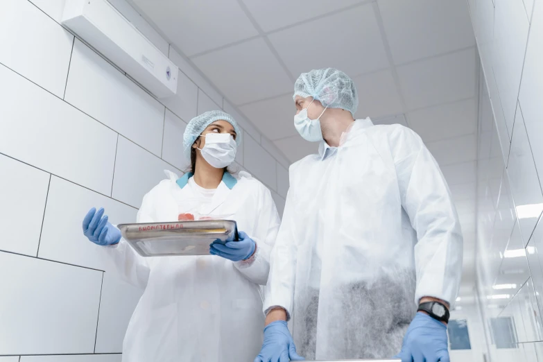 two medical professionals in white gowns and blue gloves