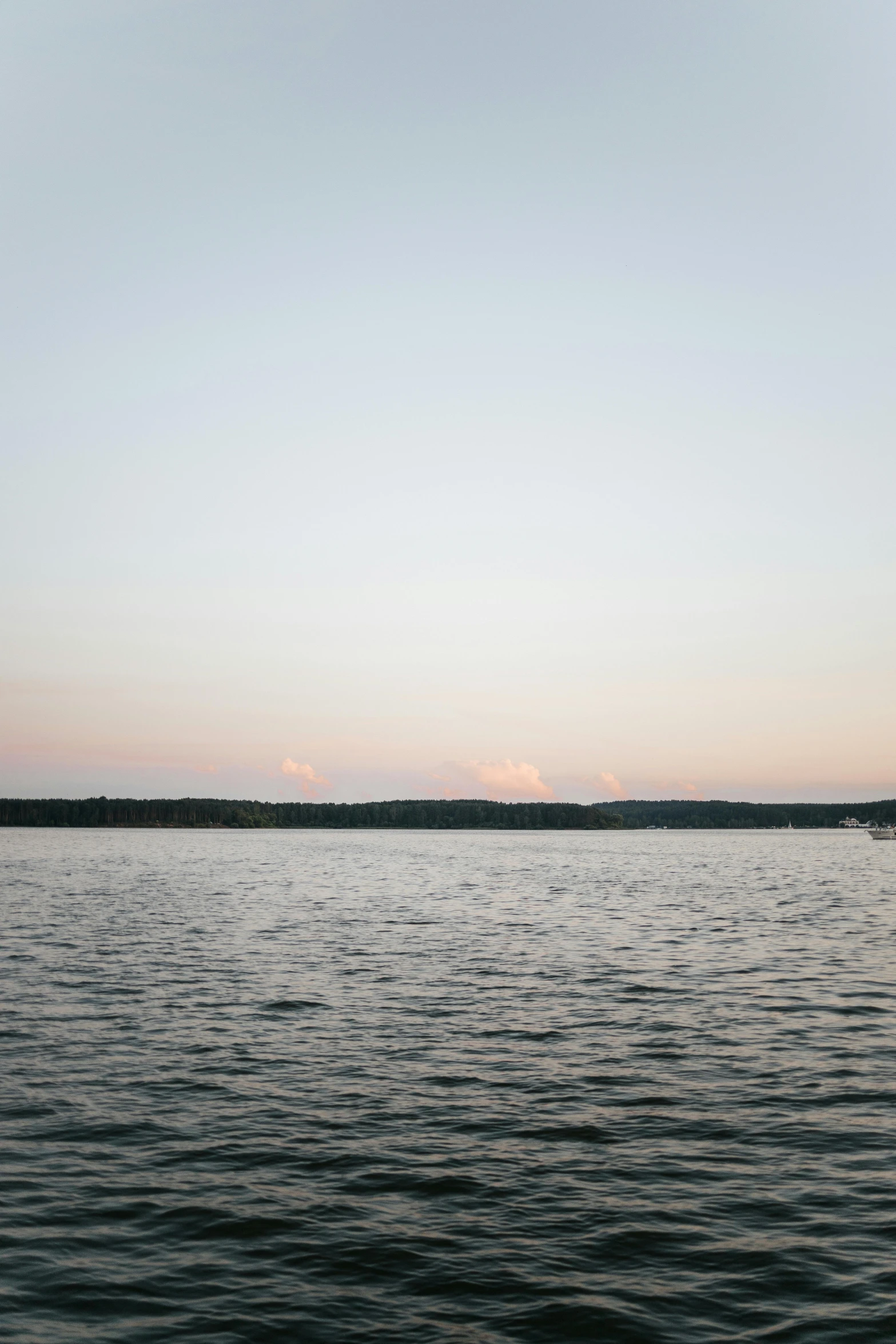 a po of the water during sunset, with a light house in the distance