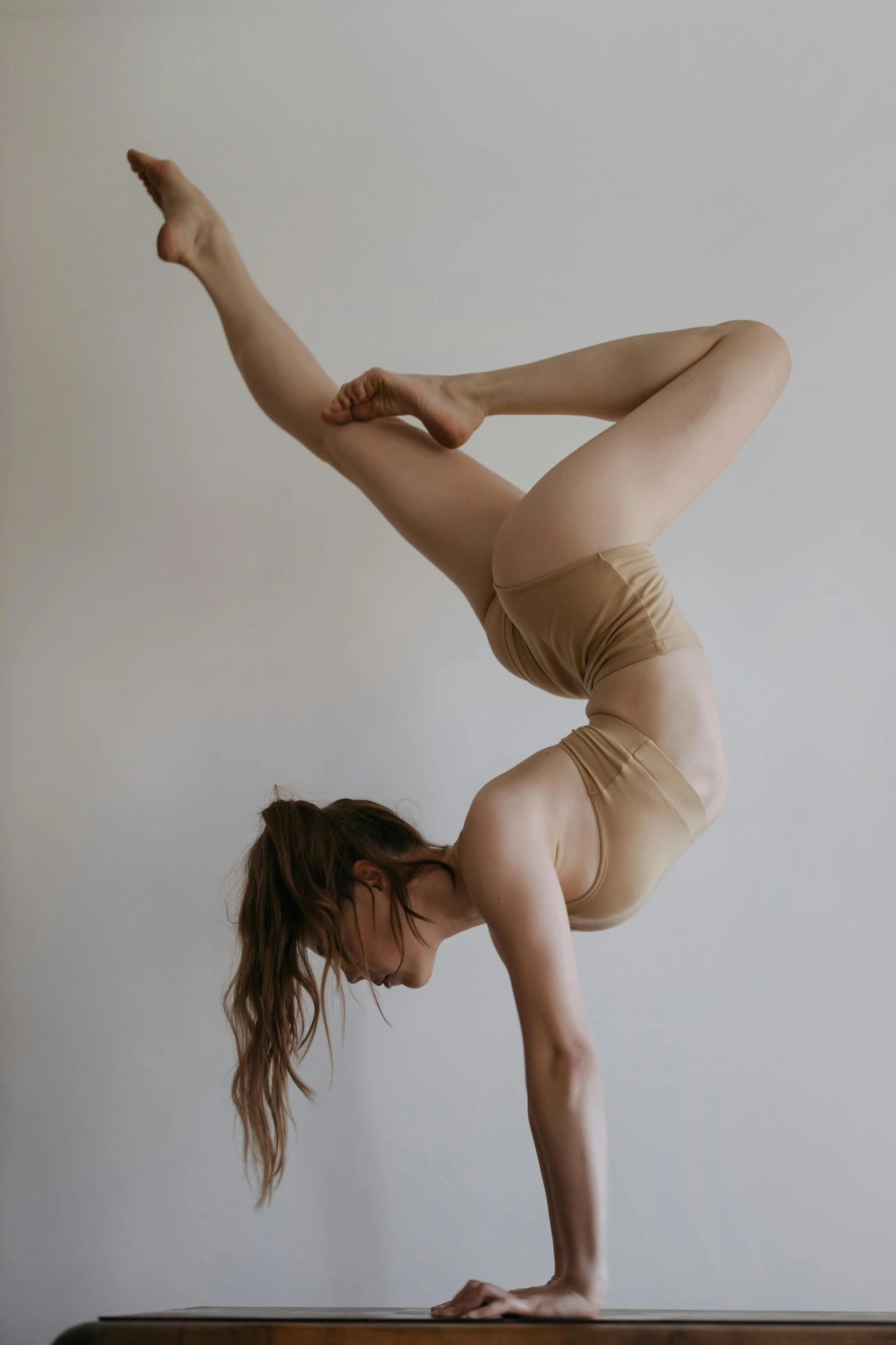 a woman does a downward hand stand on top of a bed