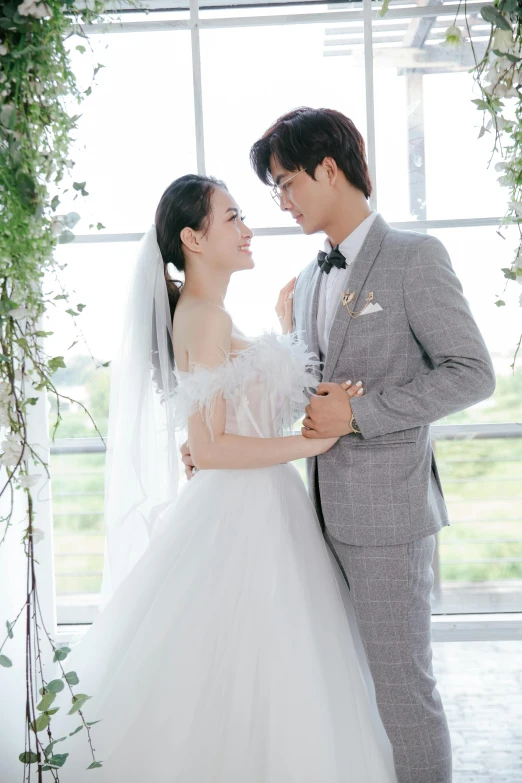 a newly wed couple is smiling together in front of an arch with foliage and flowers