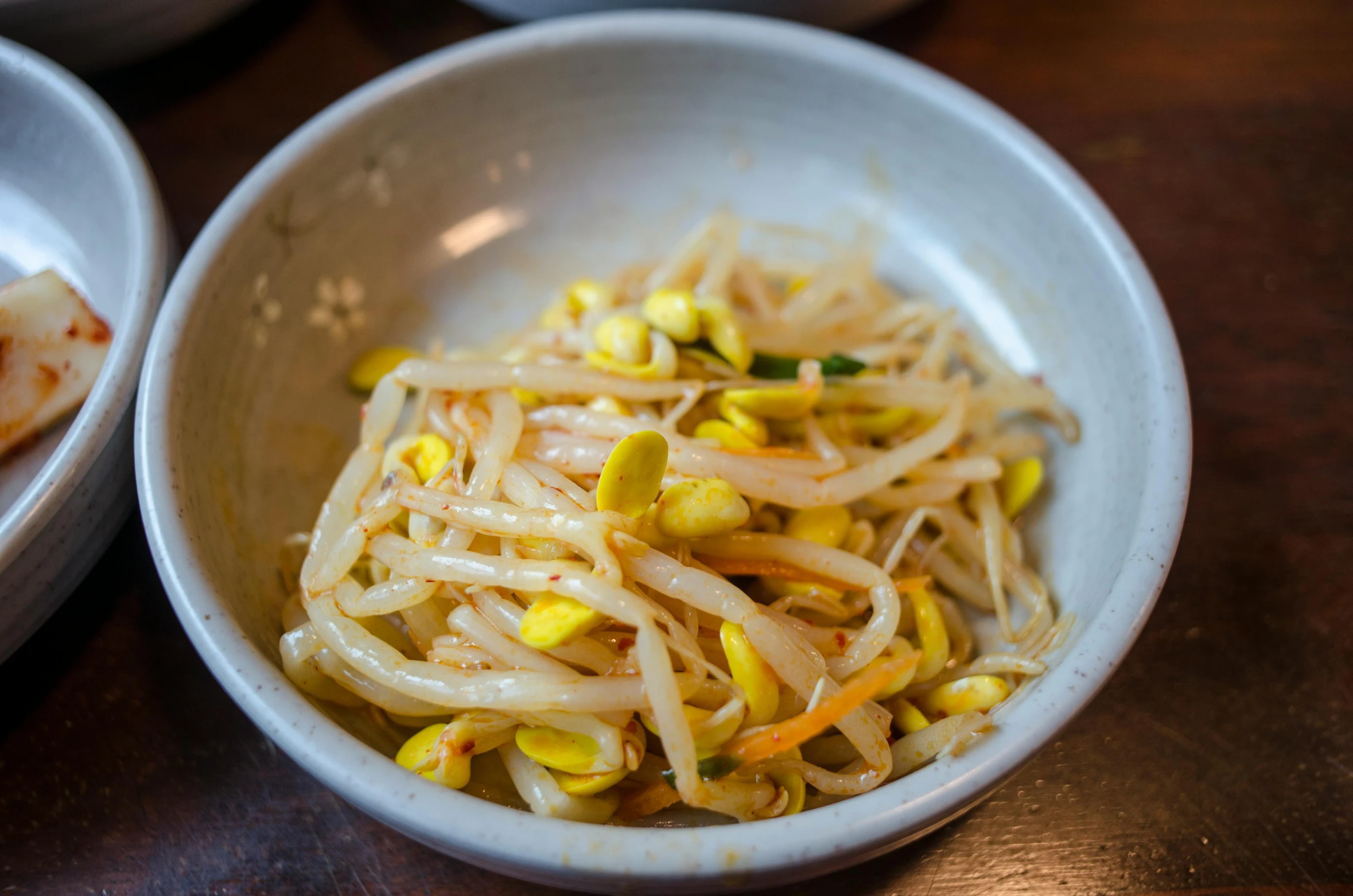 there is a white bowl with noodle and corn in it