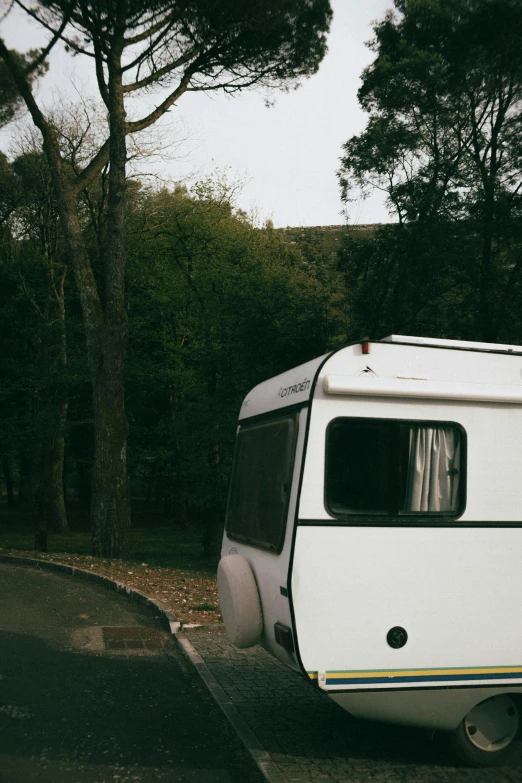 a trailer on the street next to trees