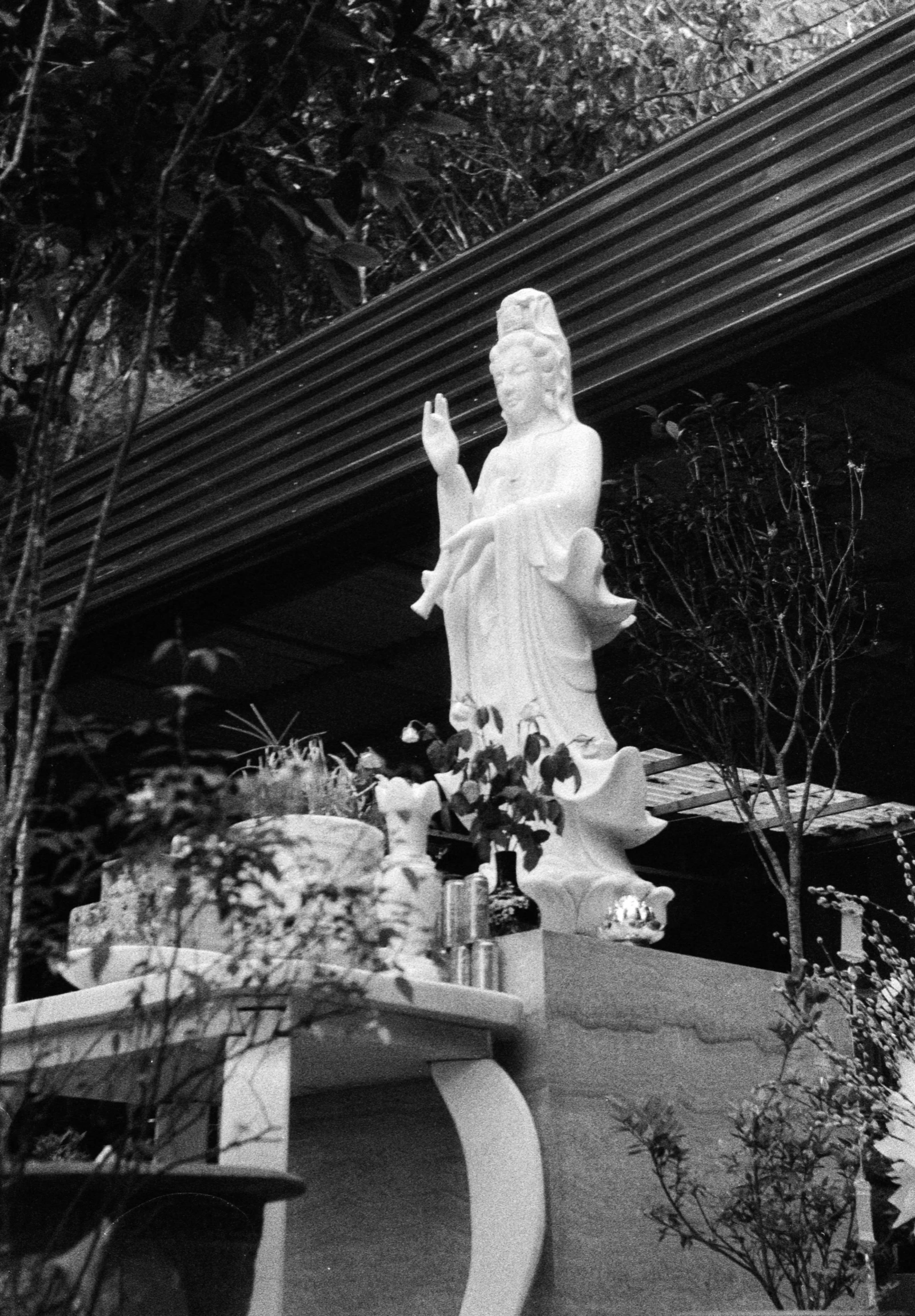 the statue is next to a bench with flowers