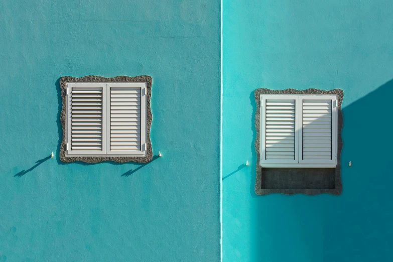 two small windows with the shadow of an umbrella on a wall