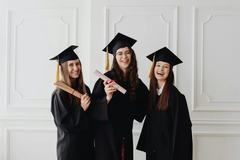 three graduates smile and pose for a po together