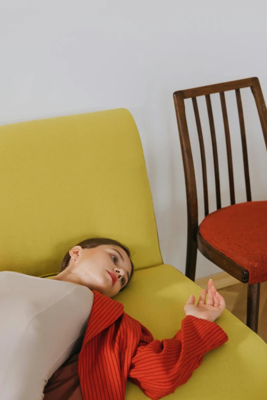 a person sitting on a couch with a yellow chair behind them